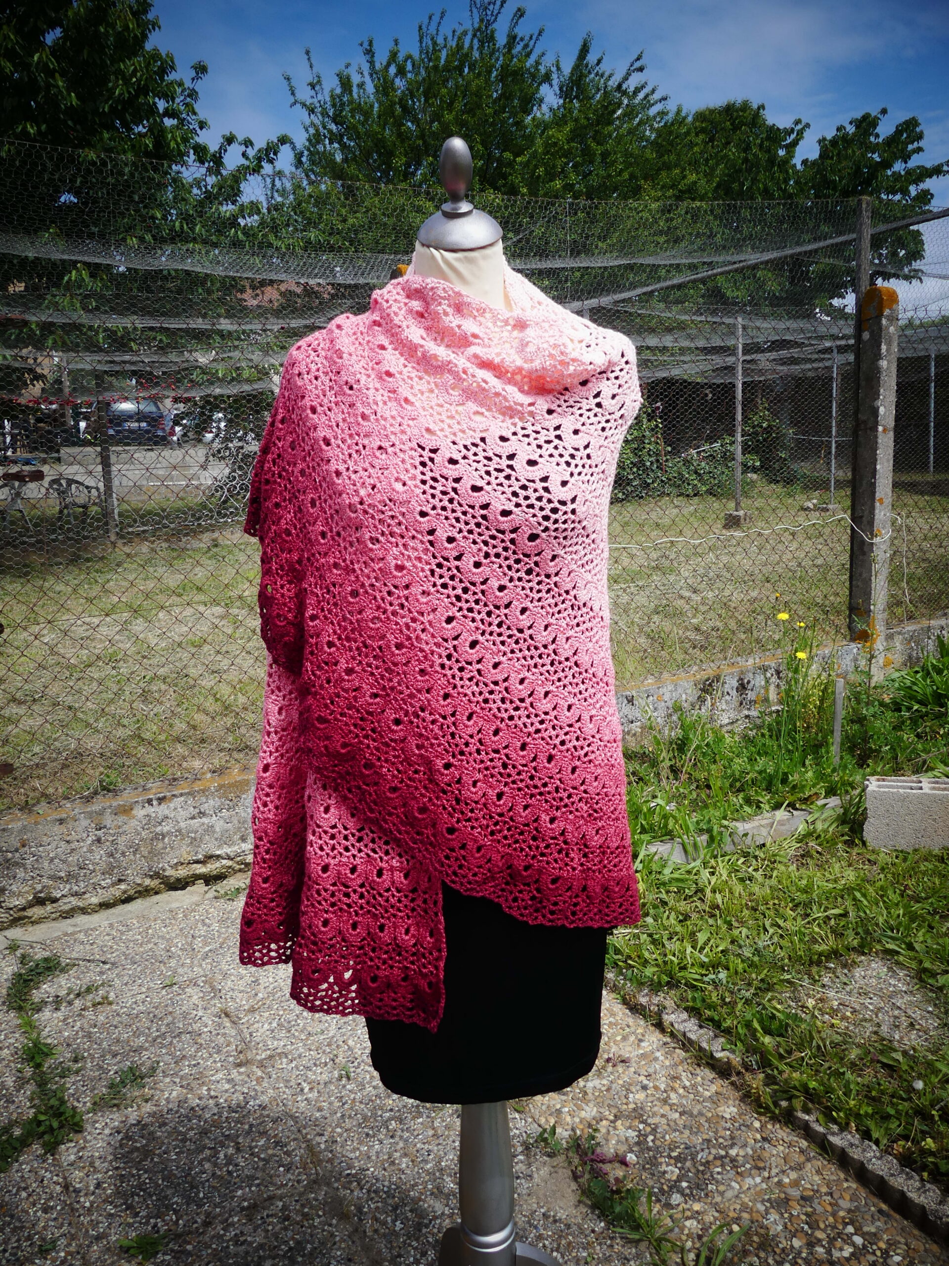 Châle crocheté main dégradé rose à motif ajouré dentelle, porté sur mannequin, étole artisanale élégante et légère